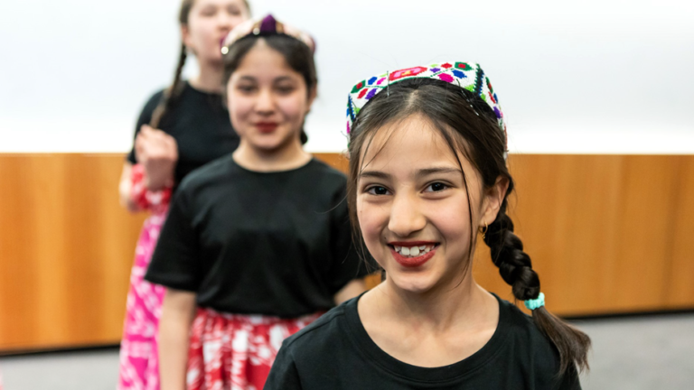 children in Uyghur dress smiling at camera
